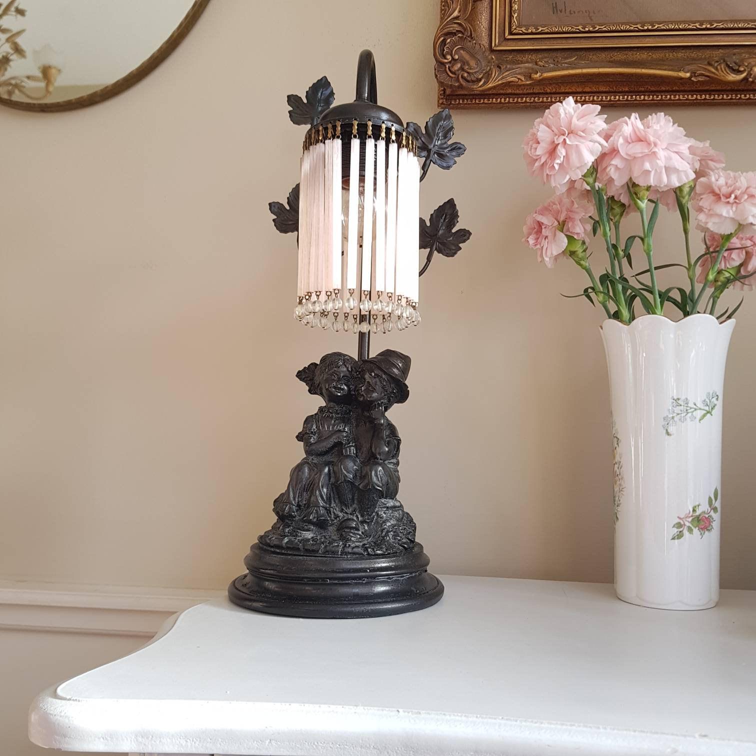 French Art Nouveau Table Lamp with Seated Children Statue and Pink Fringe Shade, 1930s Lighting for Bedroom or Side Table